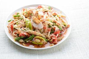 Papaya Salad with Satled Eggs, Pound chilies and garlic then place sliced tomato, eggplant and salted egg. Add fish sauce, lemon, sugar, chopped papaya then mixed all the ingredients together. photo