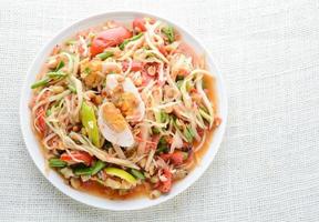 Papaya Salad with Satled Eggs, Pound chilies and garlic then place sliced tomato, eggplant and salted egg. Add fish sauce, lemon, sugar, chopped papaya then mixed all the ingredients together. photo