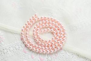 collar de perlas sobre fondo de tela blanca, primer plano de perlas de vidrio