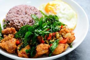 Crispy chicken cooked with green basil, served with steamed rice and fried egg, hot and spicy dish with basil leaves. photo