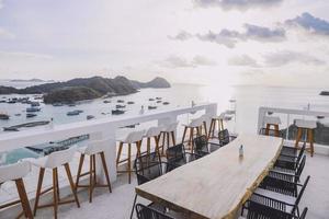 mesa de café al aire libre y sillas en la azotea con vista al mar