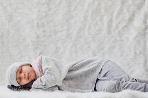 Cute boy sleeping wearing winter clothes, beanie, scarf and gloves photo