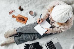 una niña escribiendo palabras de invierno en un cuaderno para el fondo del concepto de invierno foto