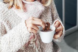 una chica disfrutando de unas galletas y una taza de chocolate caliente en la temporada de invierno