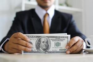 Businessman counting a hundred dollar bills on office desk photo