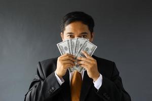 hombre de negocios codicioso en traje que cubre su rostro con billetes de dólar. concepto de corrupción y soborno foto