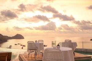 cafetería acogedora y romántica con mesa y sillas en la azotea con vistas al mar y al atardecer foto