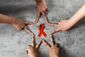 Red ribbon on hands for AIDS and cancer campaign background photo