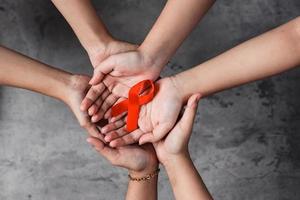 Red ribbon on hands for AIDS and cancer campaign background photo