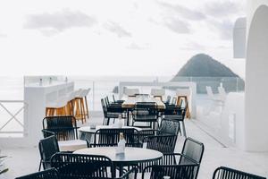 Outdoor cafe table and chairs on rooftop with sea view photo