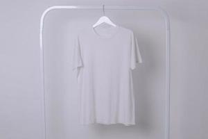 Mockup of a White Basic T-Shirt Hanging From a Clothing Rack photo