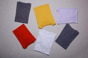 colección de coloridas maquetas de camisetas dobladas sobre fondo gris. plantilla plana en T foto