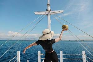 Girl holding a coconut on boat deck with sea background photo