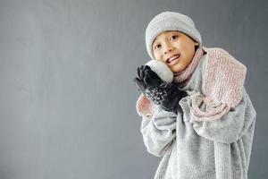 A boy wearing winter clothes and playing snow ball photo