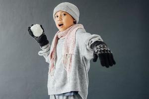 A boy wearing winter clothes and playing snow ball photo