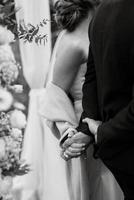the bride and groom tenderly hold hands photo