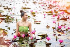 Young Asian women in Traditional dress in the boat and pink lotus flowers in the pond.Beautiful girls in traditional costume.Thai girl in retro Thai dress, Thai girl in traditional dress costume photo