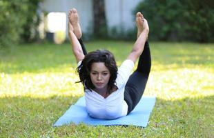 joven mujer de raza mixta estirada en la espalda en compañero de yoga. foto