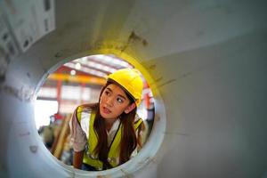 la capataz de la trabajadora o el trabajo del trabajador en el sitio de la fábrica revisan la máquina o los productos en el sitio. ingeniero o técnico revisando material o máquina en planta. industrial y fábrica. foto