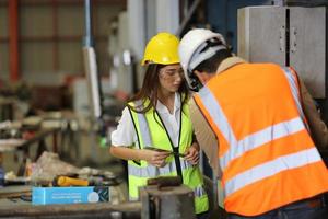 el capataz de los trabajadores de la industria o el trabajo de los trabajadores en el sitio de la fábrica revisan la máquina o los productos en el sitio. ingeniero o técnico revisando material o máquina en planta. industrial y fábrica. foto