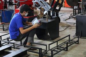 Industrial engineer or worker wearing a helmet while standing in a heavy industrial factory. The Maintenance looking of working at industrial machinery and check security system setup in factory. photo