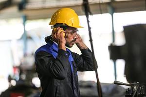 Professional industrial factory employee working with machine part, checking and testing industrial equipment and robot arms in large Electric electronics wire and cable manufacturing plant factory photo