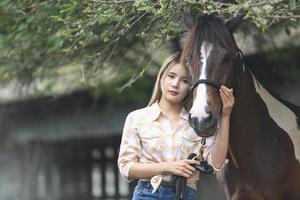 mujer joven con su caballo en la luz del atardecer. fotografía al aire libre con una modelo de moda. estado de ánimo de estilo de vida foto