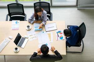 Top view of group of multiethnic busy people working in an office, Aerial view with businessman and businesswoman sitting around a conference table with copy space, Business meeting concept. photo