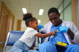 Black skin doctor checking up kid body in clinic. photo