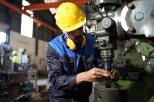 Professional industrial factory employee working with machine part, checking and testing industrial equipment and robot arms in large Electric electronics wire and cable manufacturing plant factory photo
