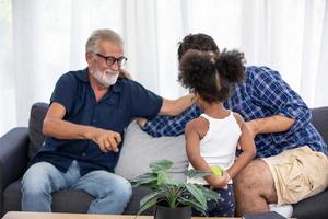 Diverse friendly family sits on the comfortable couch in cozy living room, a multiracial parents and their children enjoy time together at home photo