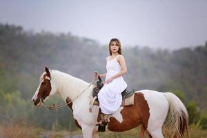 mujer joven con su caballo en la luz del atardecer. fotografía al aire libre con una modelo de moda. estado de ánimo de estilo de vida foto