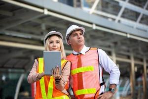 Contractor and architect looking at plan and talking about working on big project. Building in construction process interior. photo