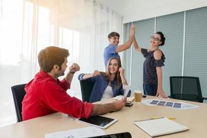 grupo diverso de jóvenes empresarios discutiendo un proyecto de trabajo mientras se sientan juntos en una mesa en una oficina moderna. concepto de coworking foto