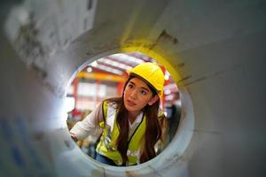 la capataz de la trabajadora o el trabajo del trabajador en el sitio de la fábrica revisan la máquina o los productos en el sitio. ingeniero o técnico revisando material o máquina en planta. industrial y fábrica. foto