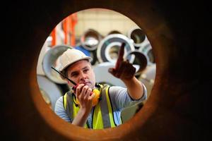 el capataz de los trabajadores de la industria o el trabajo de los trabajadores en el sitio de la fábrica revisan la máquina o los productos en el sitio. ingeniero o técnico revisando material o máquina en planta. industrial y fábrica. foto