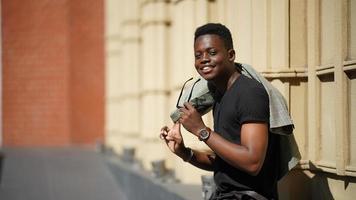 hombre afroamericano divirtiéndose caminando en el centro de la ciudad - joven feliz disfrutando del tiempo una puesta de sol al aire libre - estilo de vida de generación milenaria y concepto de actitud positiva de la gente foto