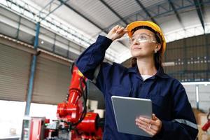 Portrait of a Professional Heavy Industry Engineer Worker Wearing Uniform, Glasses and Hard Hat in a Steel Factory. Beautiful Female Industrial Specialist Standing in Metal Construction Facility. photo