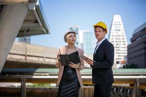 el ingeniero y la mujer de negocios revisando el portapapeles en el edificio del sitio de construcción. el concepto de ingeniería, construcción, vida urbana y futuro. foto