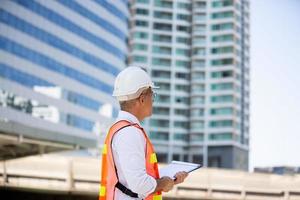 el ingeniero revisando el portapapeles en el edificio del sitio de construcción. el concepto de ingeniería, construcción, vida urbana y futuro. foto