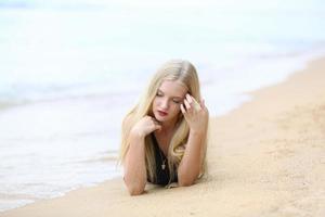 hermosa mujer rubia en bikini negro disfruta del verano en la playa. foto