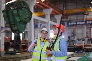 Men industrial engineer wearing a safety helmet while standing in a heavy industrial factory. The Maintenance looking of working at industrial machinery and check security system setup in factory. photo