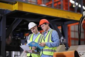 el capataz de los trabajadores de la industria o el trabajo de los trabajadores en el sitio de la fábrica revisan la máquina o los productos en el sitio. ingeniero o técnico revisando material o máquina en planta. industrial y fábrica. foto