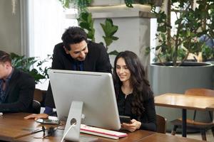 Business professionals. Group of young confident business people analyzing data using computer while spending time in the office photo