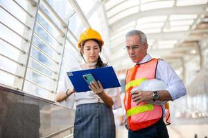 el ingeniero y la mujer de negocios revisando el portapapeles en el edificio del sitio de construcción. el concepto de ingeniería, construcción, vida urbana y futuro. foto