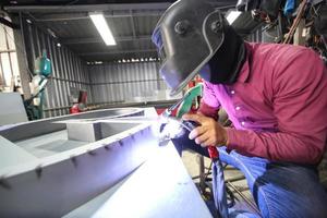 Welder used grinding stone on steel in factory with sparks, Welding process at the industrial workshop, hands with instrument in frame. photo