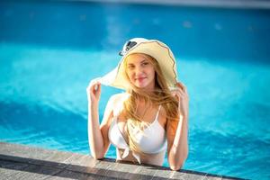 woman in white bikini tanning by the pool photo