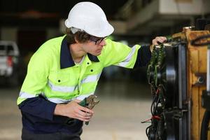 Professional industrial factory employee working with machine part, checking and testing industrial equipment and robot arms in large Electric electronics wire and cable manufacturing plant factory photo