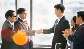 gente de negocios dándose la mano en la oficina moderna terminando una reunión exitosa foto