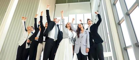 los empresarios exitosos que se unen se ensanchan mostrando una fuerte relación de comunidad de trabajadores. un equipo de hombres de negocios y mujeres de negocios que expresan un sólido trabajo en equipo en la oficina moderna. foto